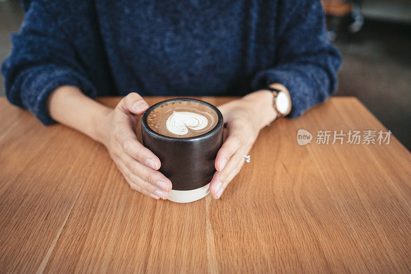 一位女士在一家咖啡店里喝着热咖啡
