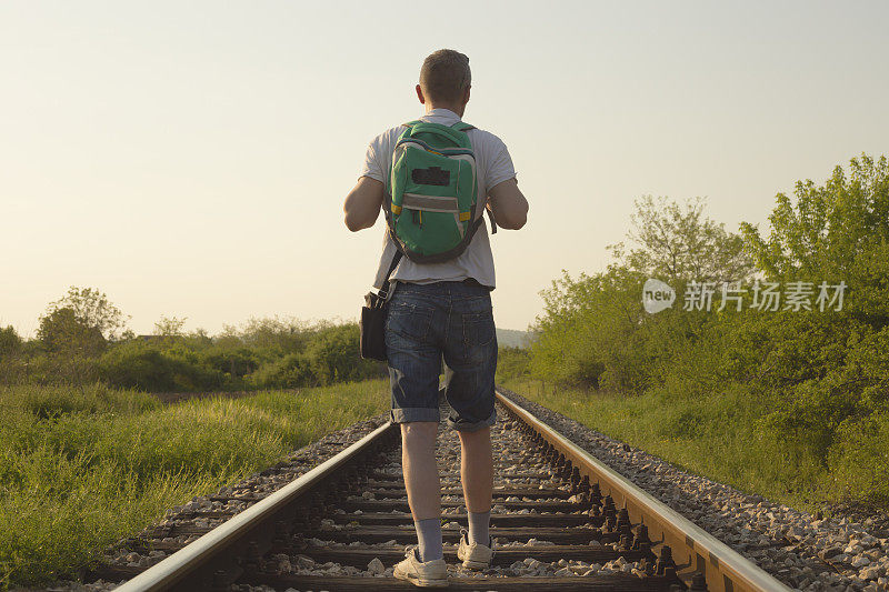 成年男子背着背包在铁路上徒步旅行