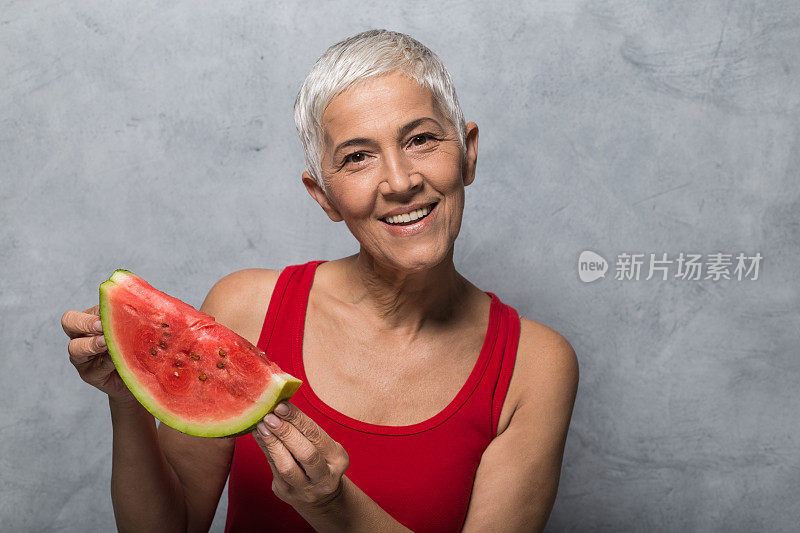 快乐成熟的女人拿着西瓜片