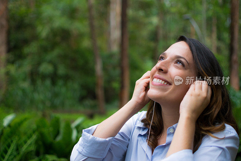 美丽的女人在户外戴着耳机听音乐