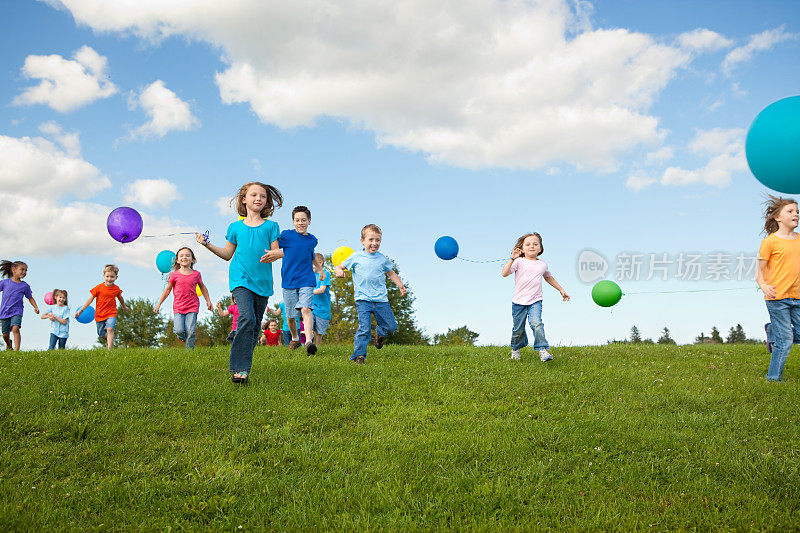 一群快乐的孩子拿着气球奔跑