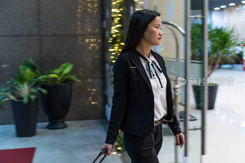 年轻的亚洲商务女性在出差时走进酒店大堂