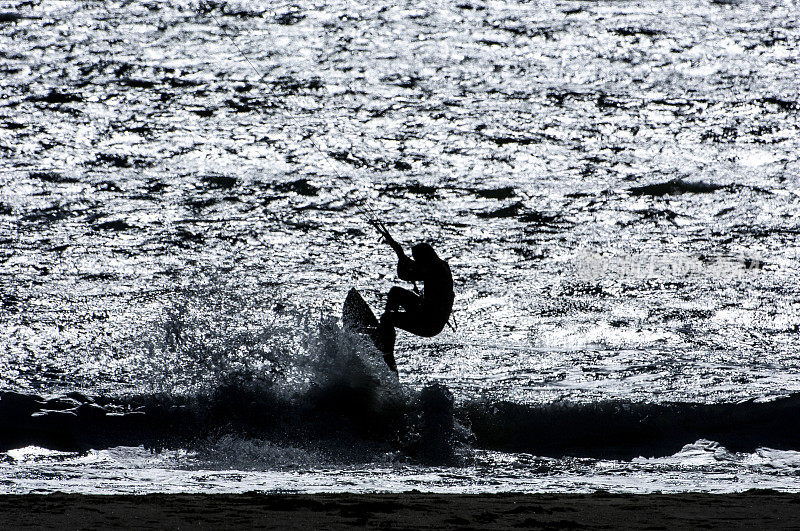 在加利福尼亚海岸冲浪的人们的剪影