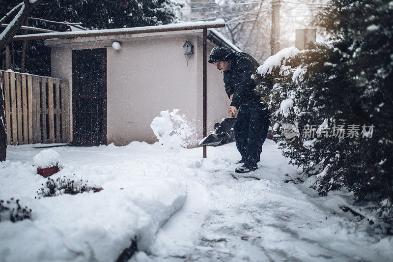 老人正在清理后院的积雪