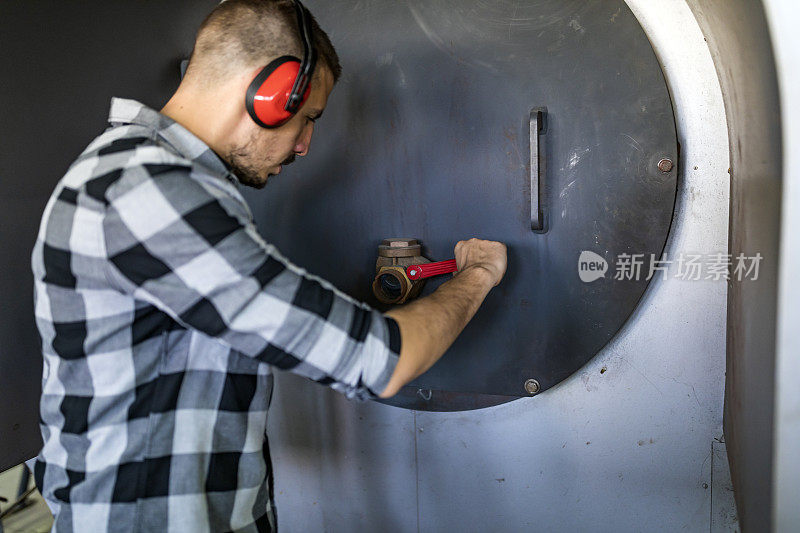 年轻的技术员正在检查锅炉房的加热系统