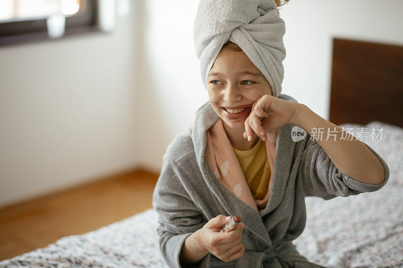 肖像的小美丽的女儿使用她妈妈的皮肤上应用化妆品