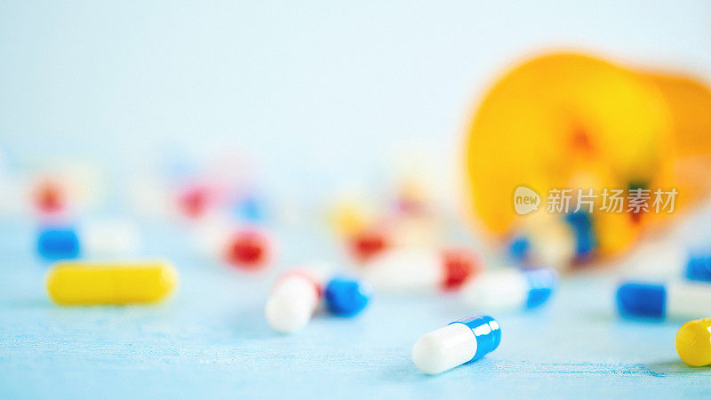 五颜六色的药丸和药瓶放在蓝色的桌子上
