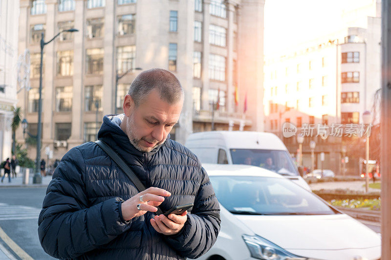一个成熟的男人拿着智能手机等优步出租车