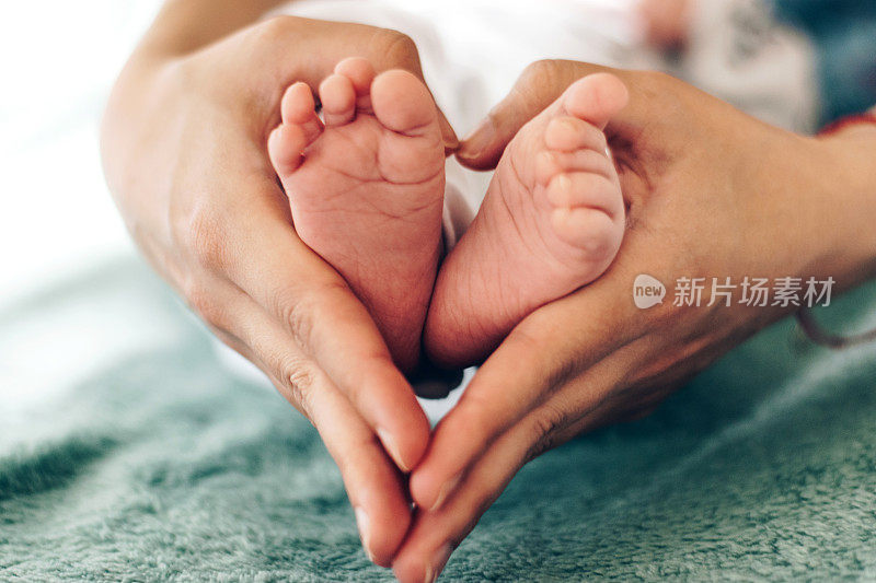 婴儿的腿在母亲的手中库存照片