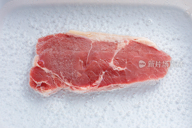 将人造牛肉浸泡在含有培养液的白色容器中。