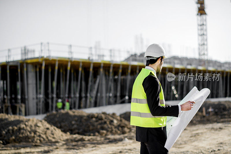 后视图的年轻建筑工程师与项目和安全帽