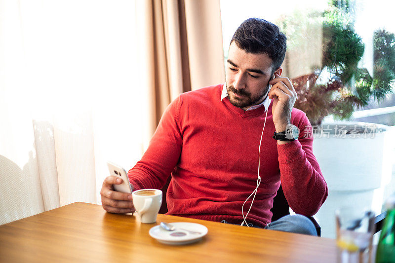 男人坐在café喝咖啡和使用手机