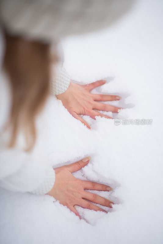 年轻女子在雪中留下手印，冬天