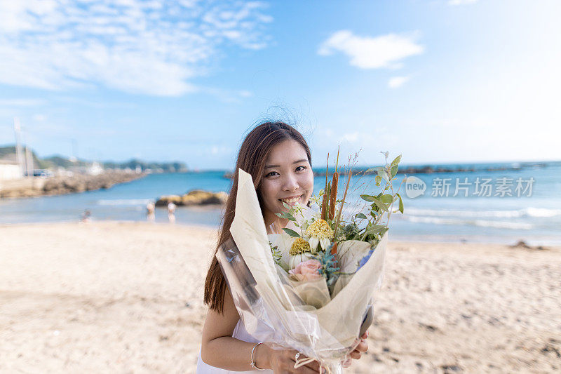 夏日沙滩上，年轻女子捧着花束