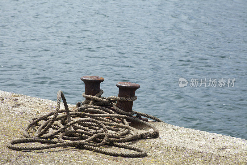 港口双系泊柱，套索堆，海背景。