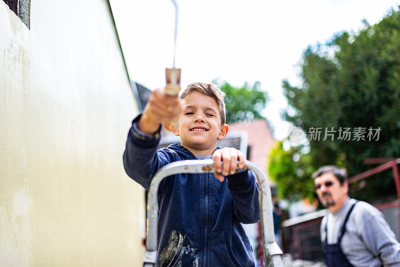 小男孩在帮他爷爷刷墙