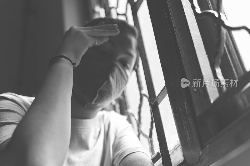 这个悲伤的女孩正在保护自己，戴着口罩，在家里自我隔离。