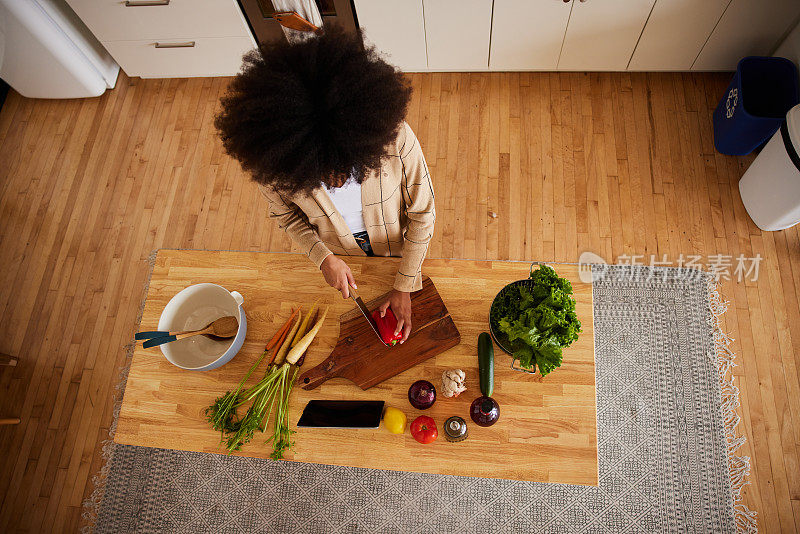 一位妇女在厨房的柜台前切菜准备晚餐
