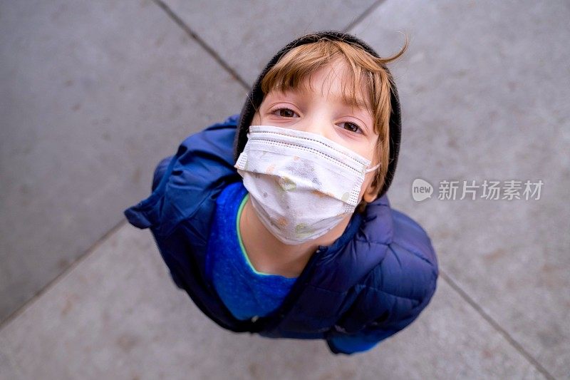 沉思烦恼的小男孩在学校用一个保护面罩看着摄像机