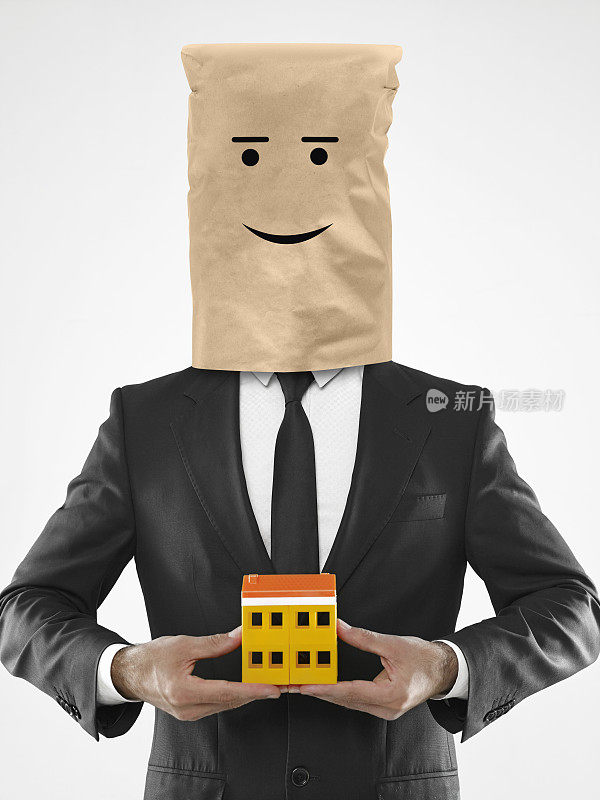商人拿着一个玩具房子，头上套着纸袋