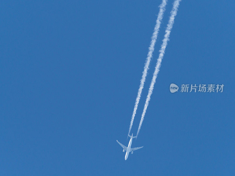飞机在蓝色的天空中飞行，后面拖着白色的水雾