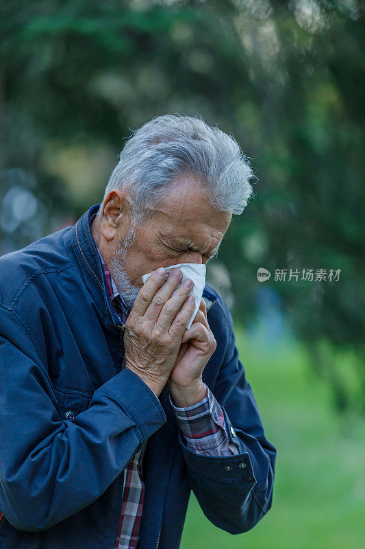 一名患季节性流感的男子在公园里散步，并用纸巾咳嗽。