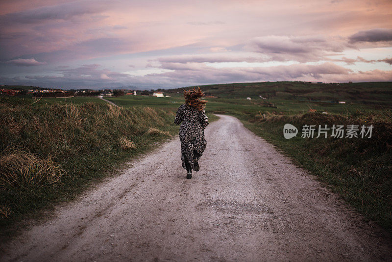 一个年轻女子的后视镜走在一条土路上