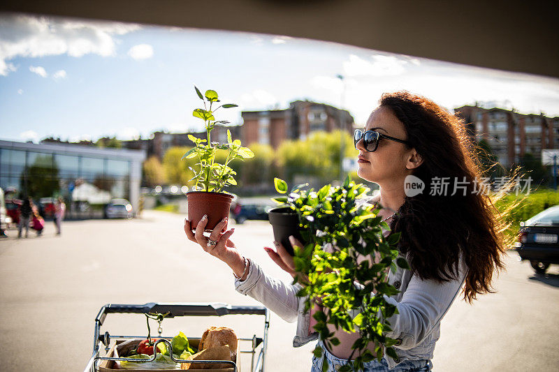 一位漂亮的年轻女子在超市买完东西，买了一些蔬菜和漂亮的花。