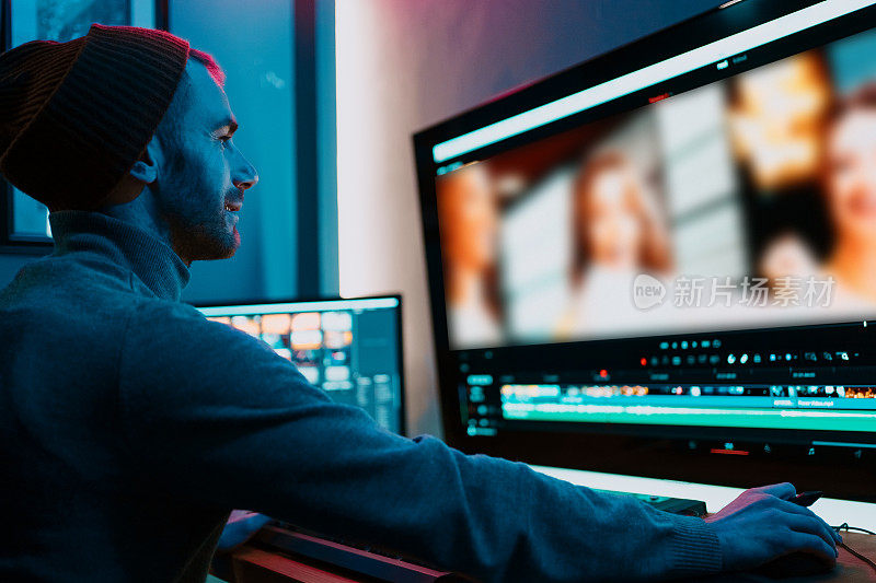 男性视频编辑在他的大屏幕个人电脑上工作