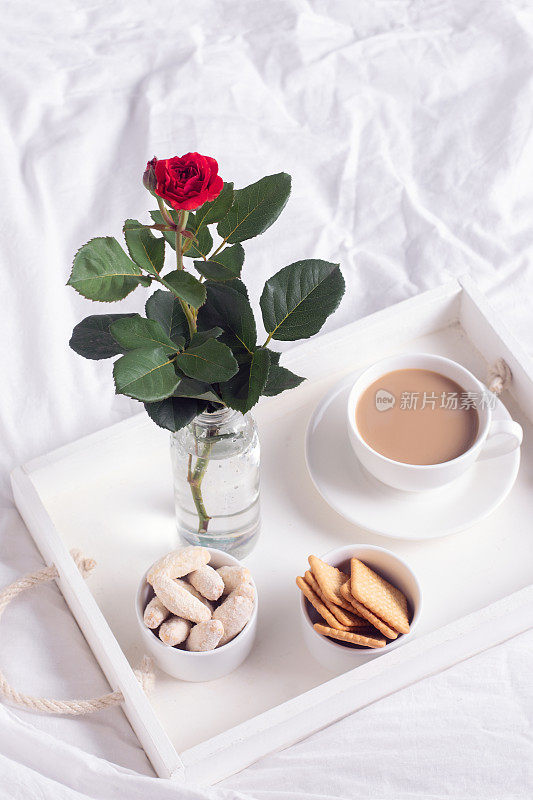 早餐在床上。白色托盘，上面放着咖啡和饼干。