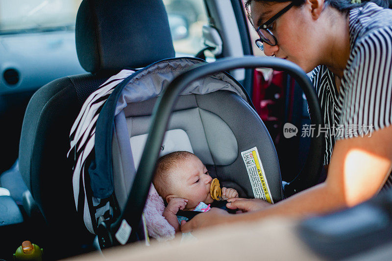 母亲把婴儿扣在汽车座椅上