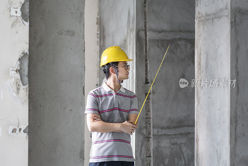 亚洲男工程师在翻新工地戴着头盔工作