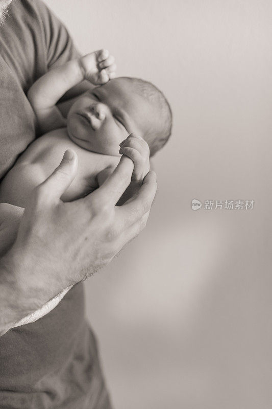 黑白照片的圣诞新生婴儿睡在他父亲的怀里