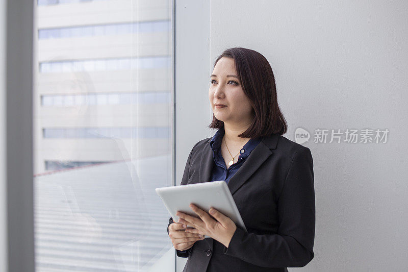 一个日本女人从办公室的窗户往外看