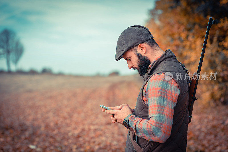 年轻的猎人在野外使用智能手机