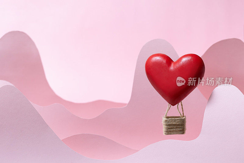 情人节或妇女节与爱情概念的背景。红色气球和剪纸心形粉红色的云和山。横幅贺卡或销售