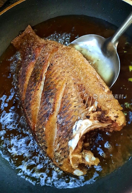 在平底锅中煎炸罗非鱼-食物准备。