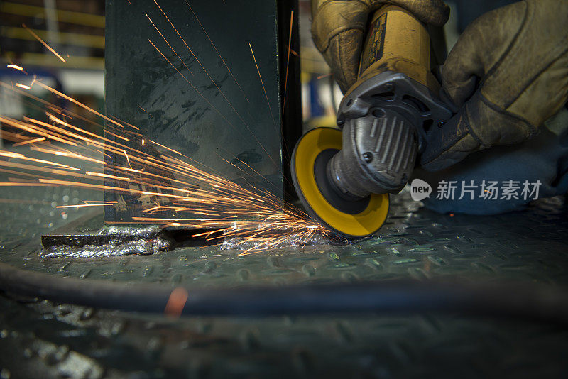 工人使用角磨工具在钢焊缝上工作，引起火花飞溅