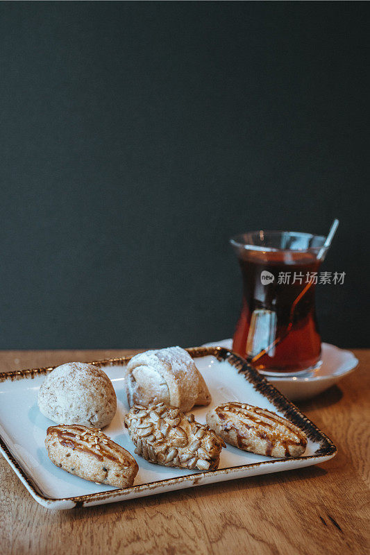 什锦或混合饼干，迷你马卡龙和彩色马卡龙，红茶(土耳其茶)，木桌上的饼干和茶，迷你acibadem饼干，咸和糖饼干