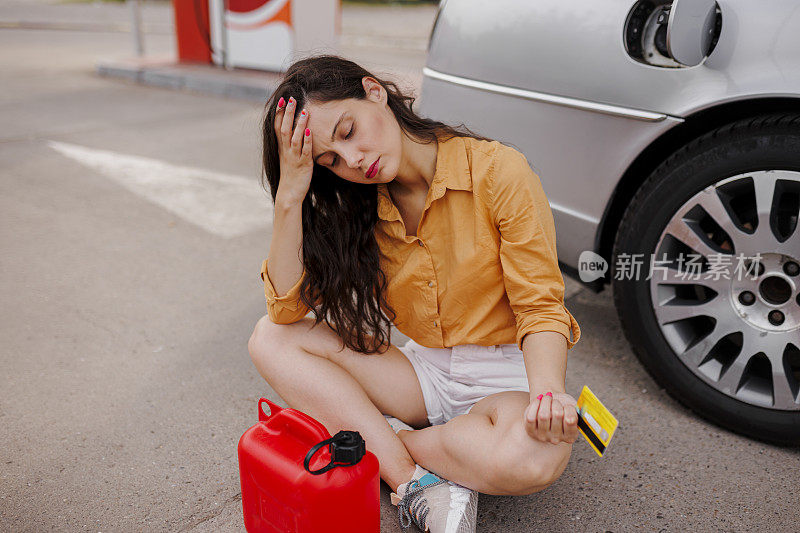 沮丧的震惊的妇女在加油站加了汽油罐