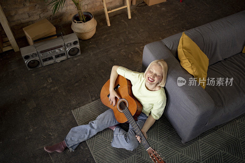 快乐的金发女郎在家里弹吉他