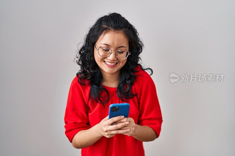 年轻的亚洲女性使用智能手机打字信息微笑和大声笑，因为有趣的疯狂的笑话。