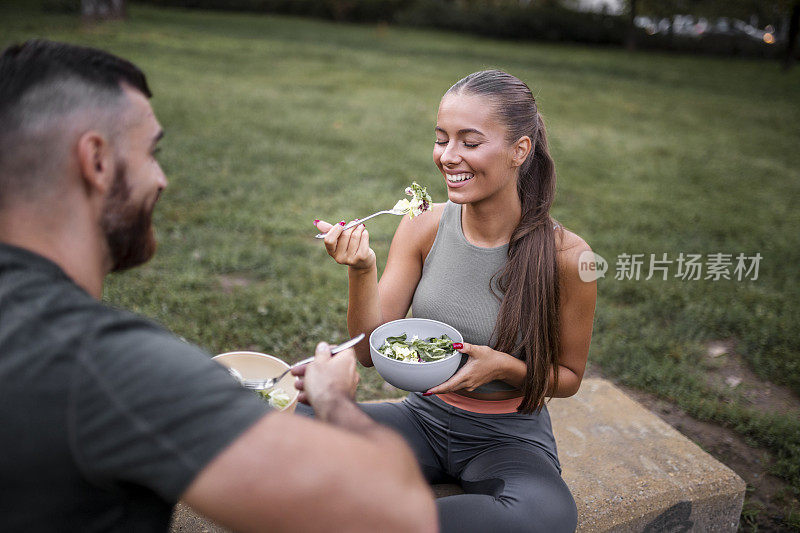 一对快乐的情侣在高强度锻炼后吃蔬菜沙拉