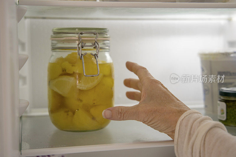 女人伸手去拿冰箱里的腌柠檬