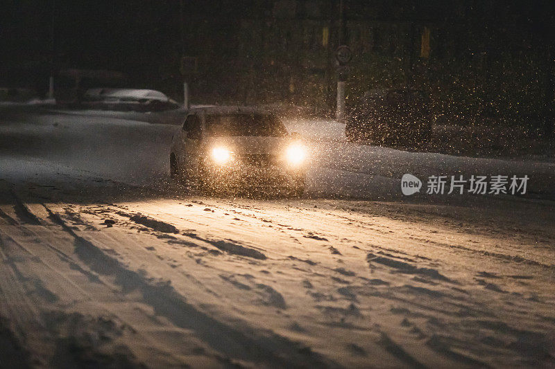 夜晚街道上的汽车。暴雪。飘落的雪在黑暗的背景。雪花。冬天的天气。气候。风暴。灯笼在黑暗中发光。光线