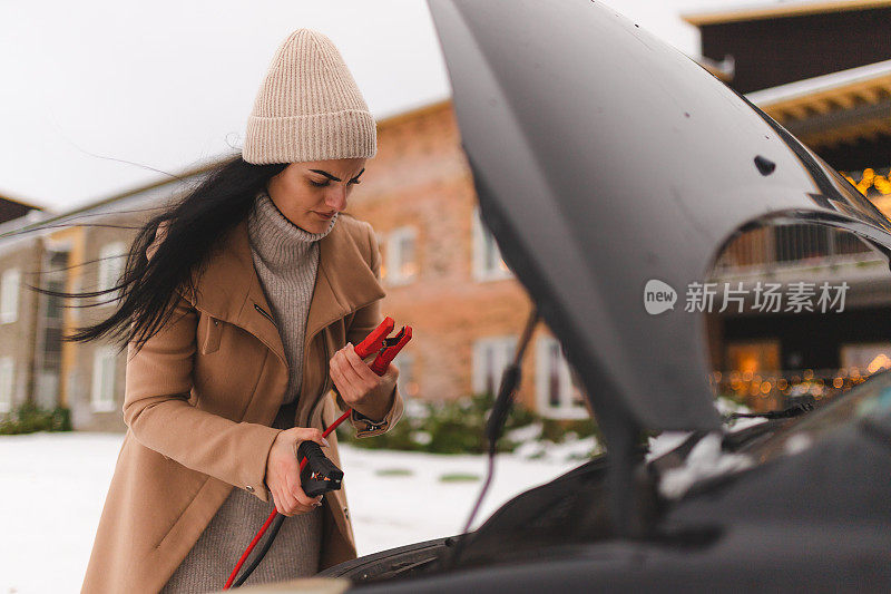 一名年轻女子试图弄清楚如何在冬天启动她的车