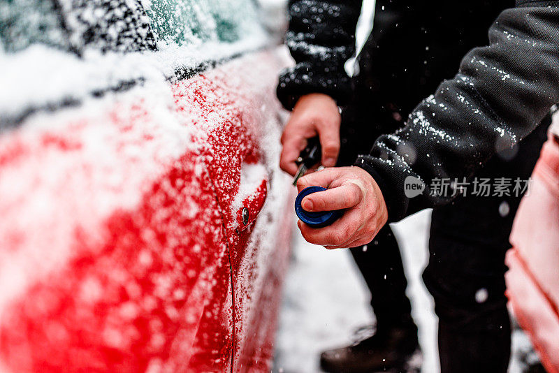 一个男人的车出了雪的问题，所以他在打开车门。