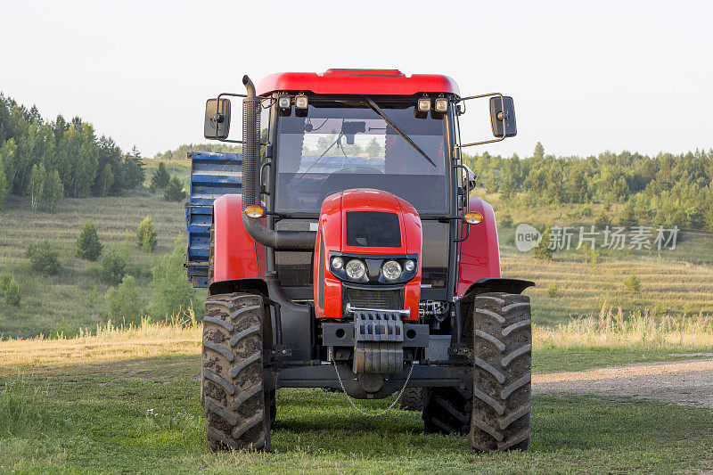 一辆红色的新拖拉机在长满青草的山坡上的特写