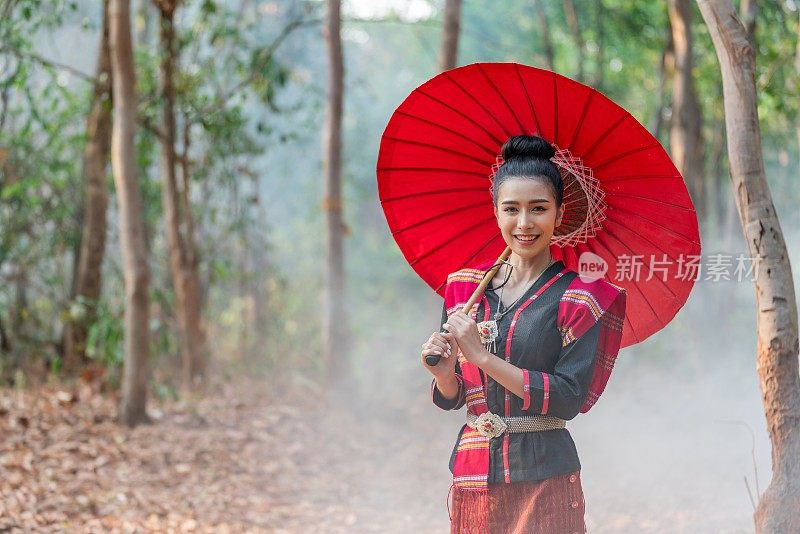 年轻美丽的亚洲女子在传统的泰国东北部是一个服装站在一头巨大的大象前面