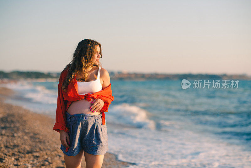 背景是在海外海滩休息的微笑孕妇